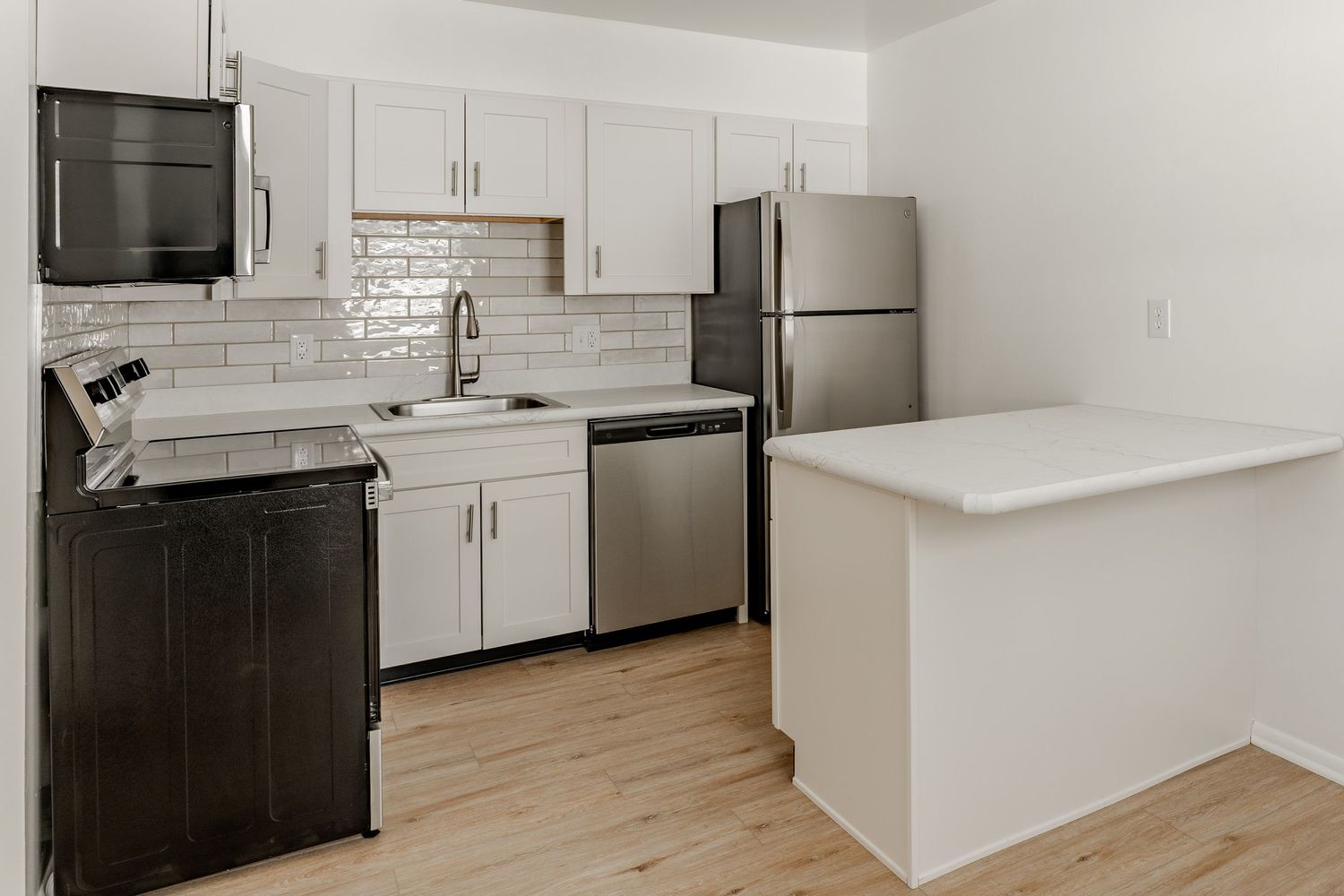 Small kitchen with white cabinets, black-and-stainless range and a quartz peninsula counter