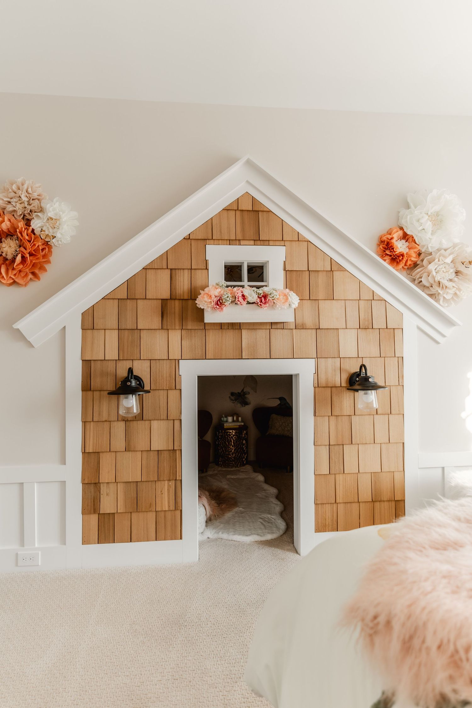 Built-in kids' playhouse nook with cedar shingle siding, a flower box window and sconce lighting