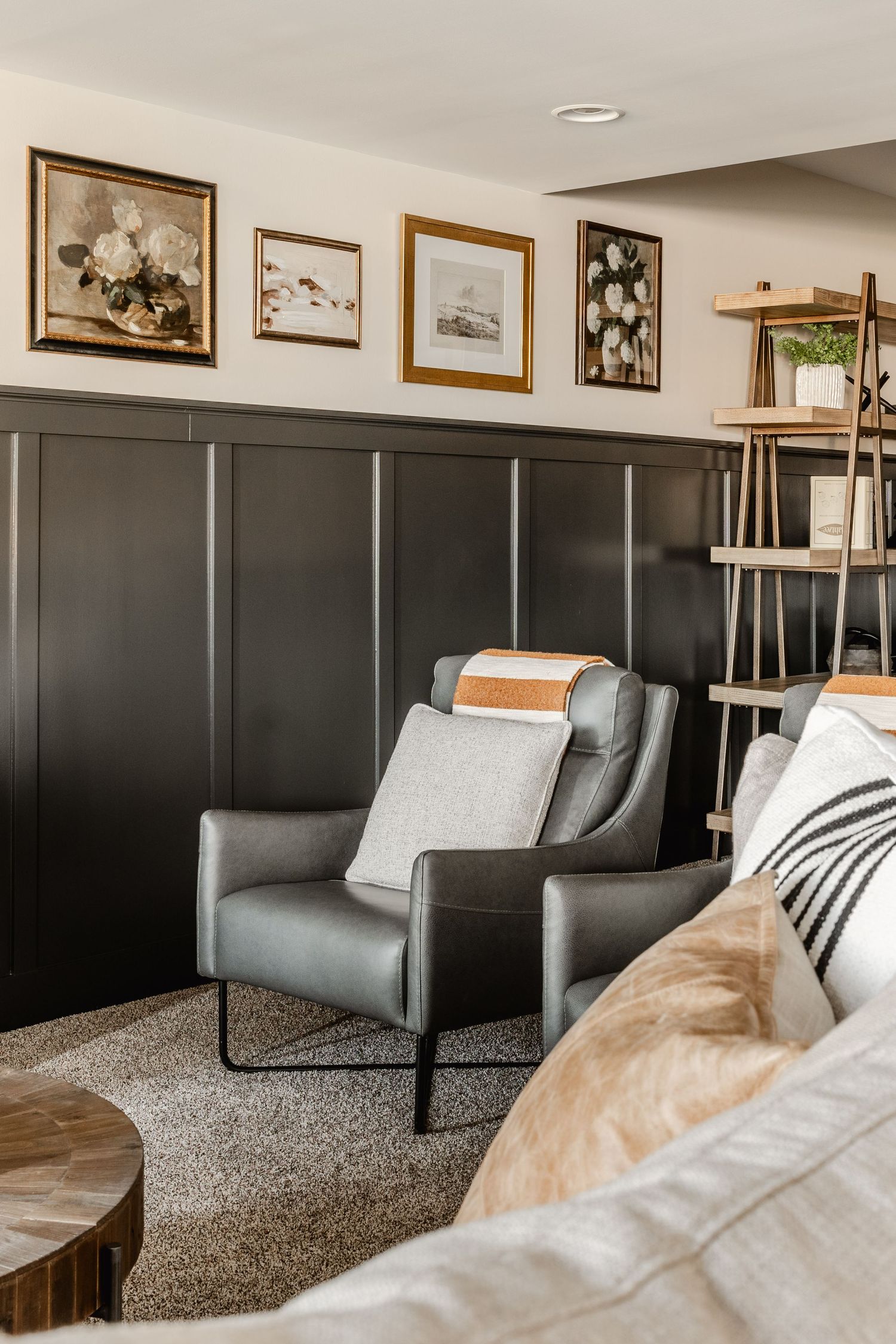 Reading nook with gray leather armchairs, a ladder bookshelf and a gallery of floral prints