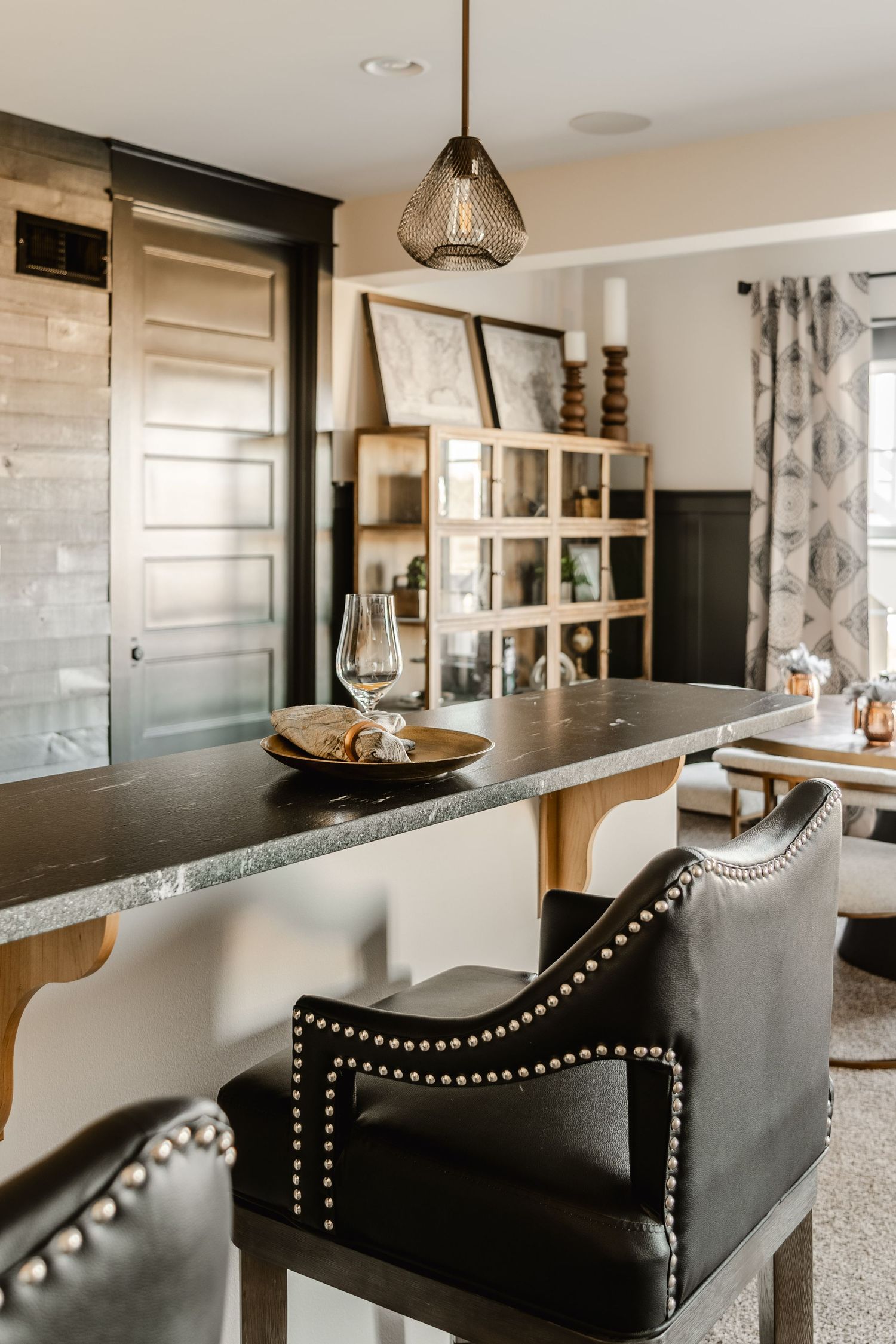 Close-up of a soapstone bar counter with nailhead leather stools and wood corbels