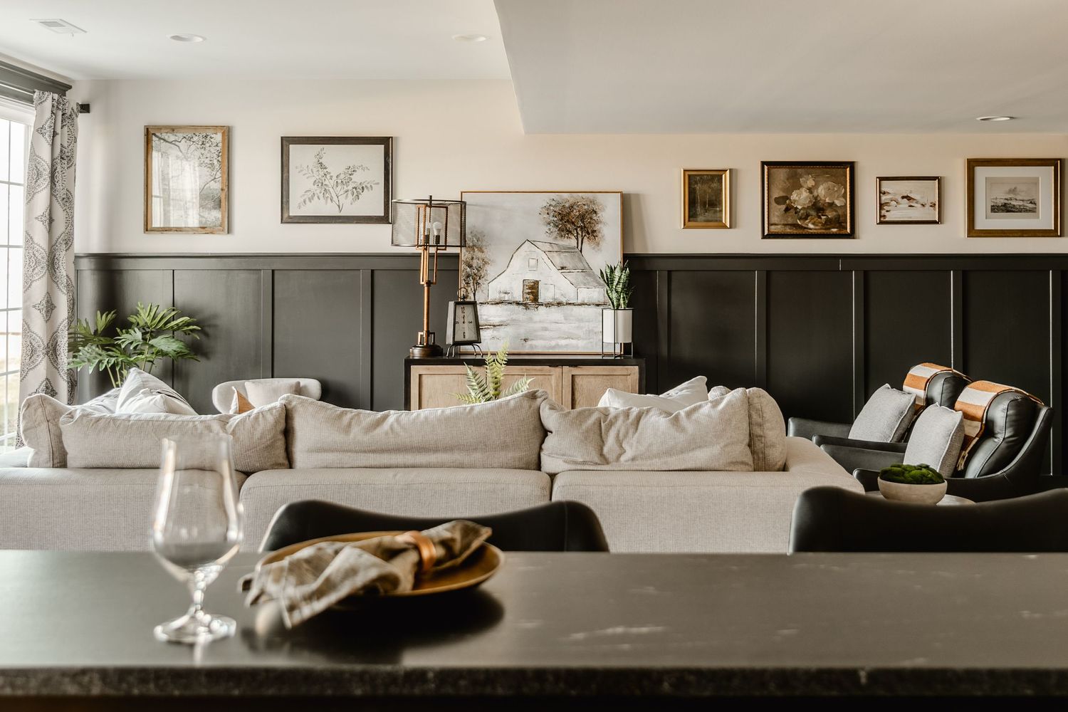 Living room with dark board-and-batten walls, a curated gallery of framed art and a cream sectional
