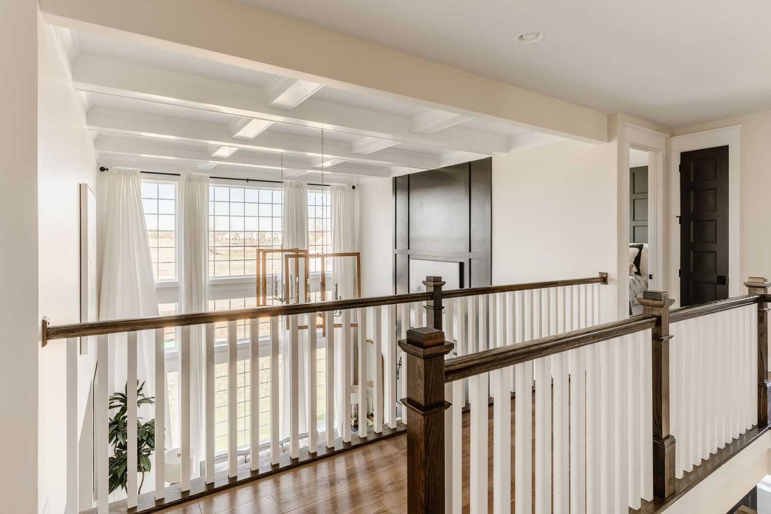 Second-floor landing with dark wood and white balusters overlooking tall arched windows