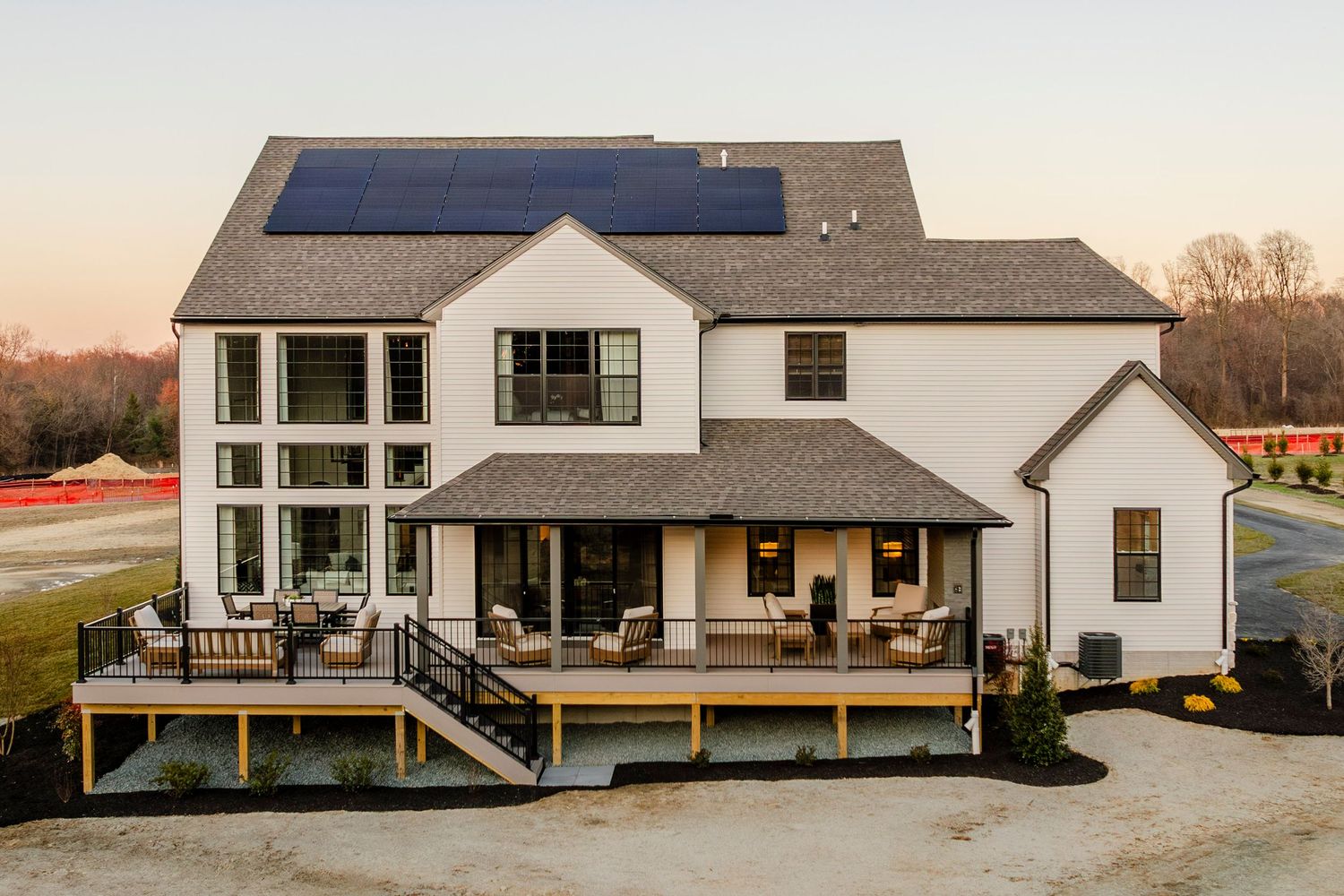 Aerial view of a white home's rear deck and porch furnished with outdoor seating and a dining table