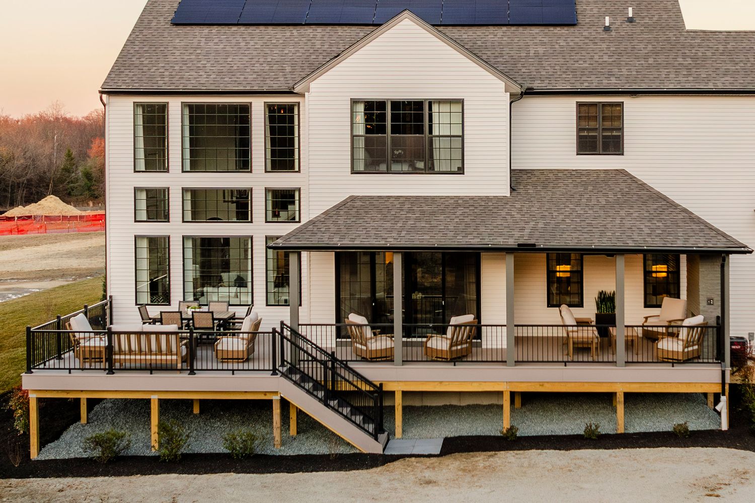 Close-up rear view of a covered porch furnished with seating beneath a solar-paneled roofline