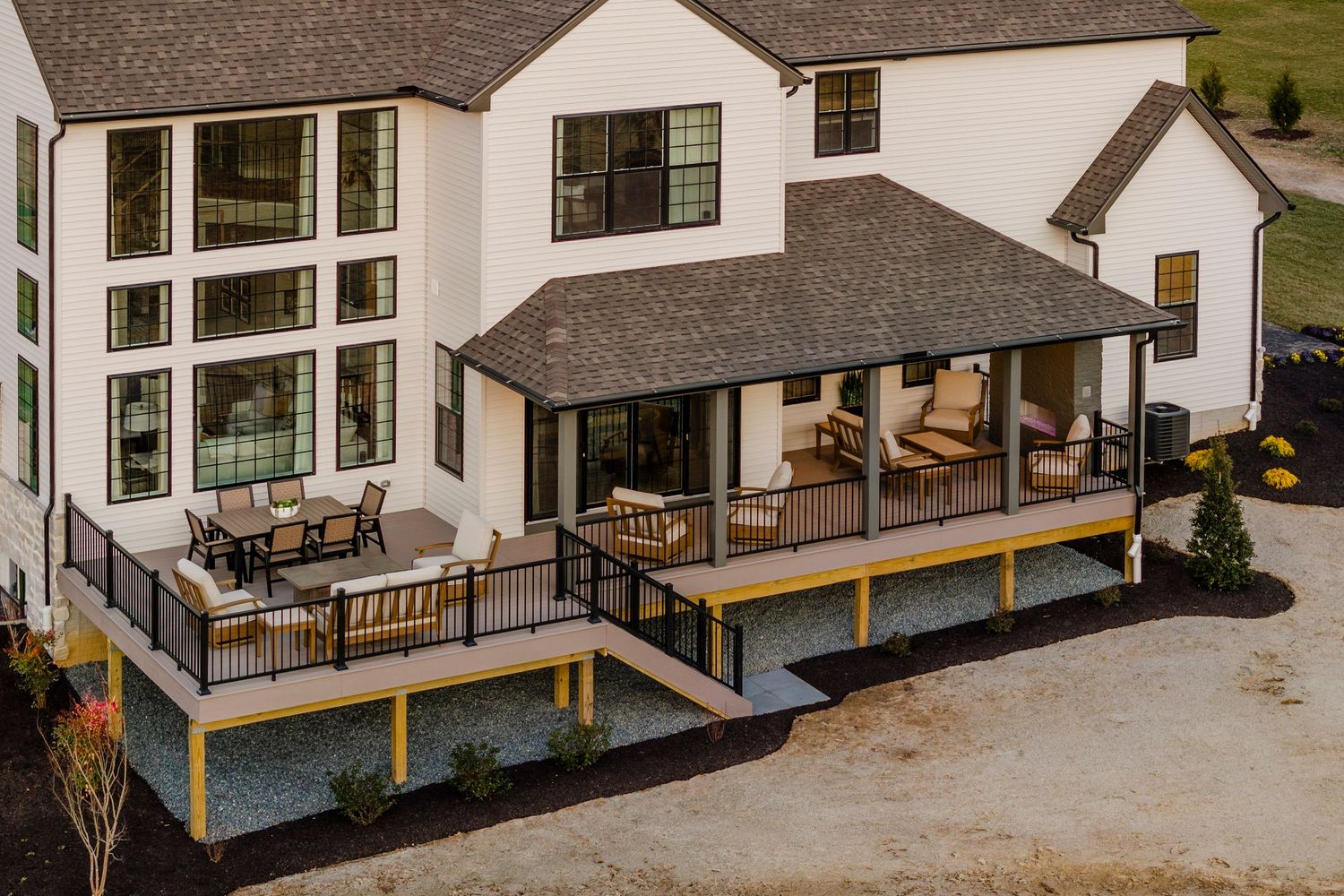 Aerial close-up of a covered back porch and deck furnished with outdoor seating and dining table