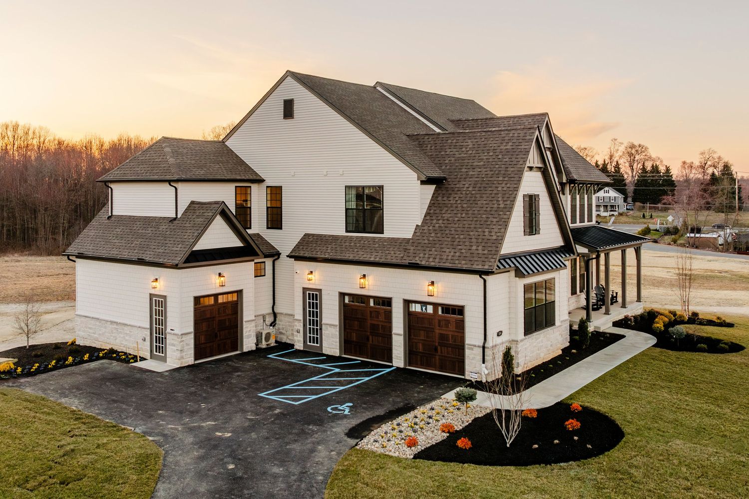 Aerial view of a stone-and-shingle home with a three-car garage and marked accessible parking