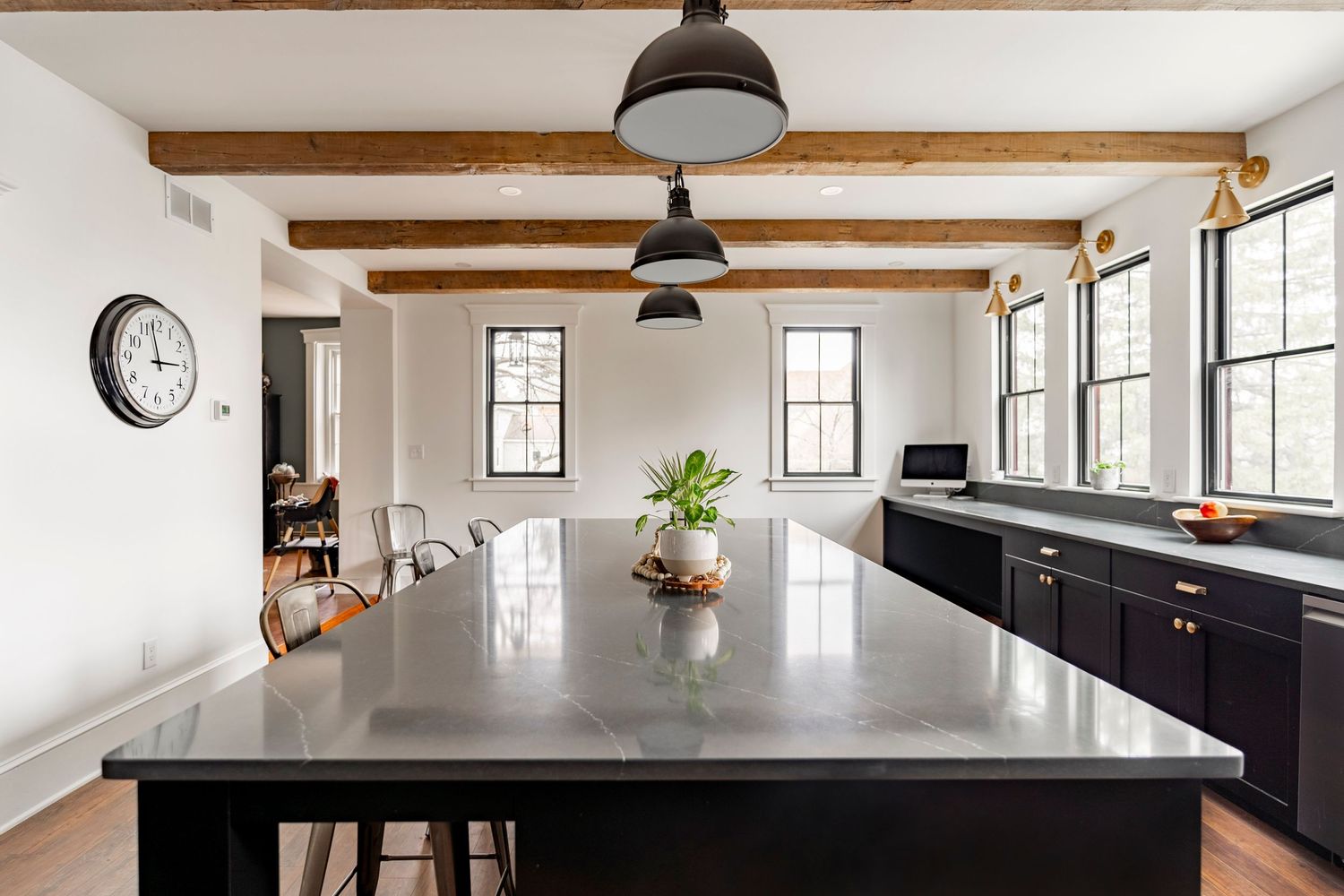 Kitchen dining nook with a black island, wall clock and view into an adjoining room