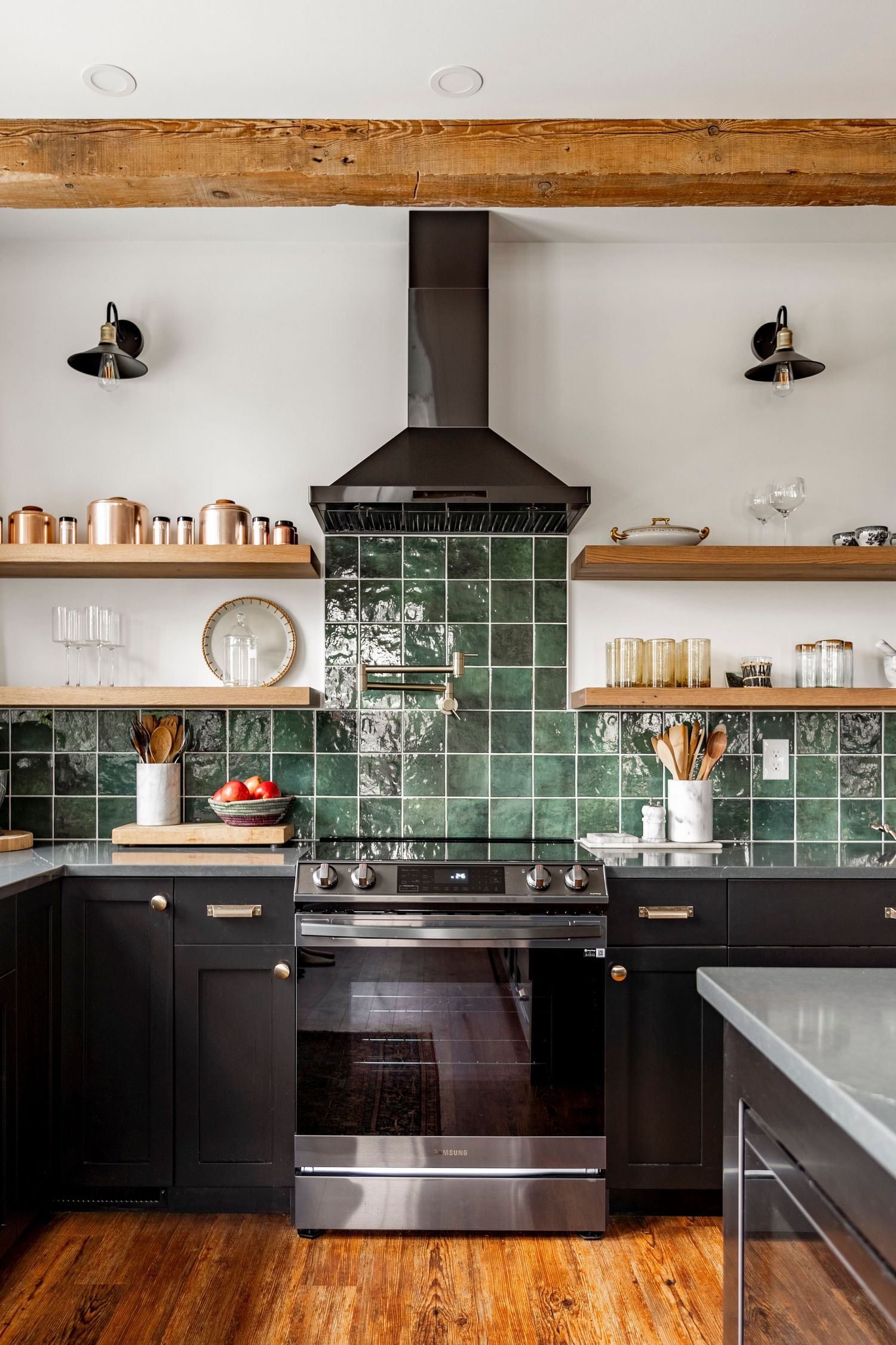 Kitchen range wall with green tile backsplash, black cabinetry and open wood shelving