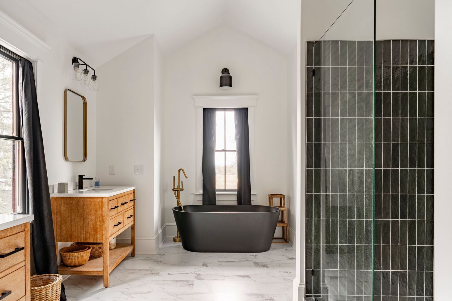 Primary bathroom with a black soaking tub, wood vanity and black tile shower