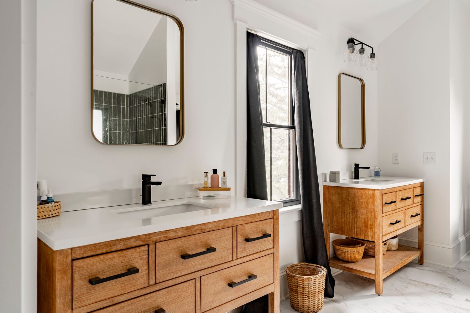 Primary bathroom with dual wood vanities, white countertops and a black curtained window