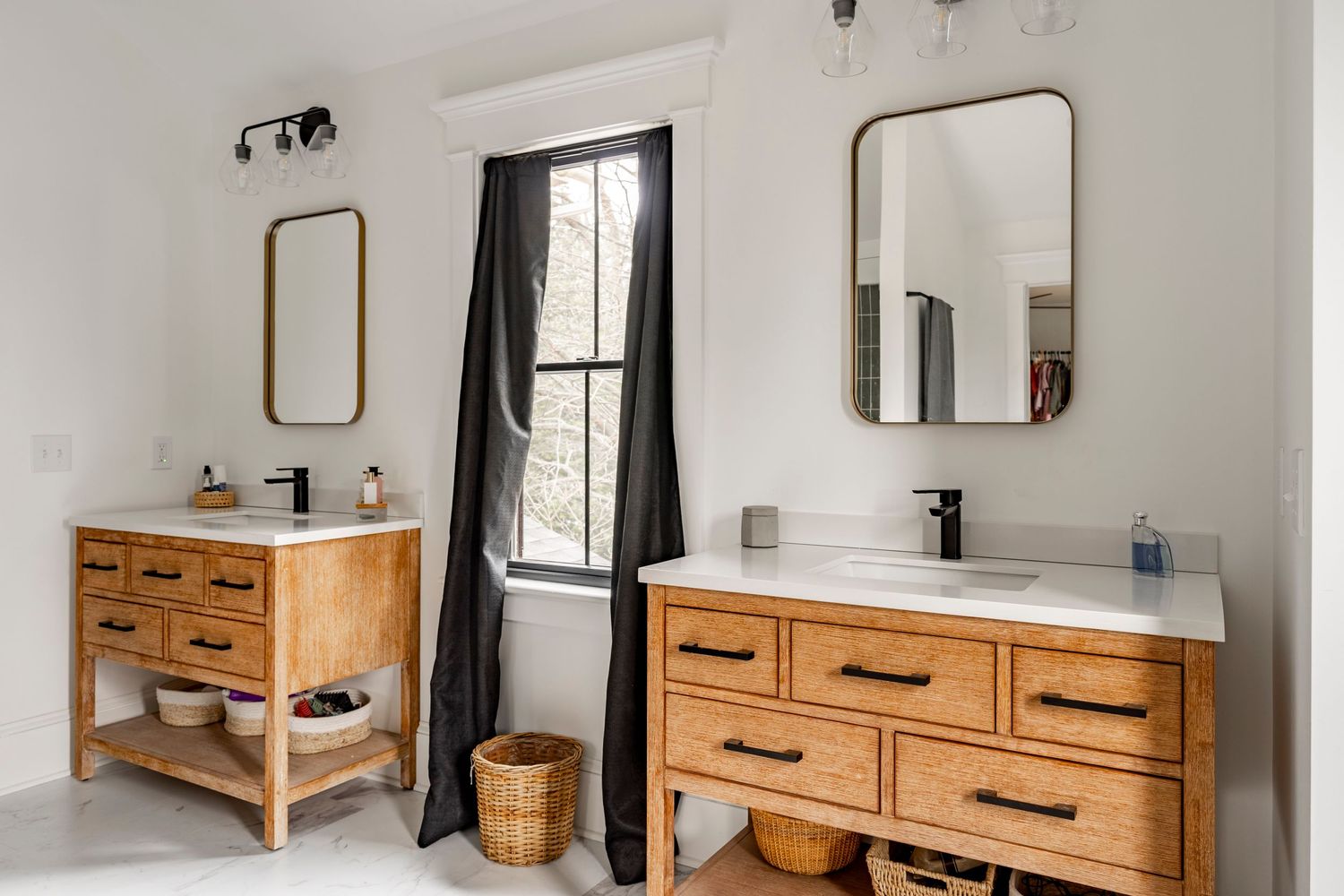 Primary bathroom vanity with wood cabinetry, white countertop and a black tile shower