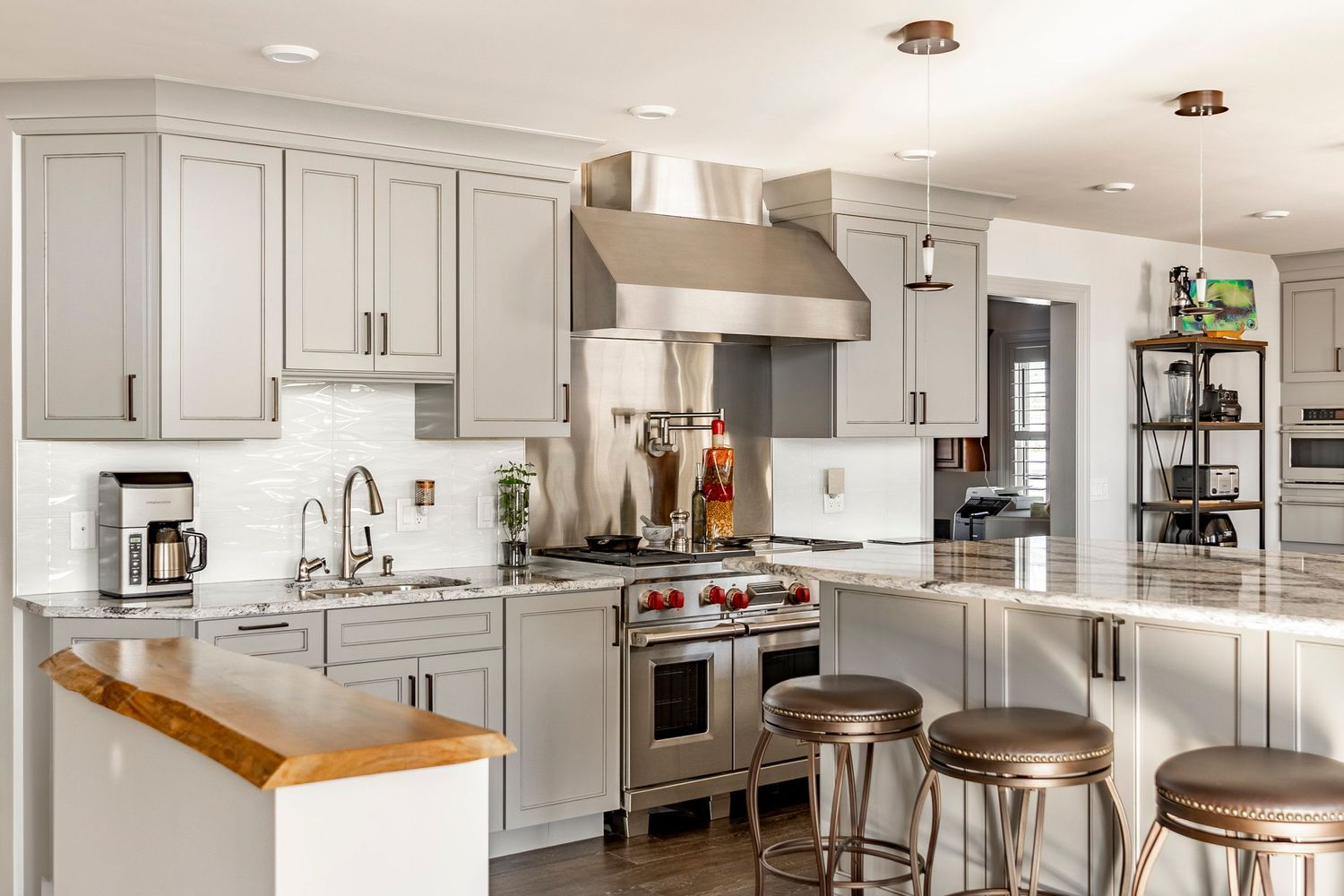 Open kitchen with gray cabinetry, granite island and industrial metal counter stools