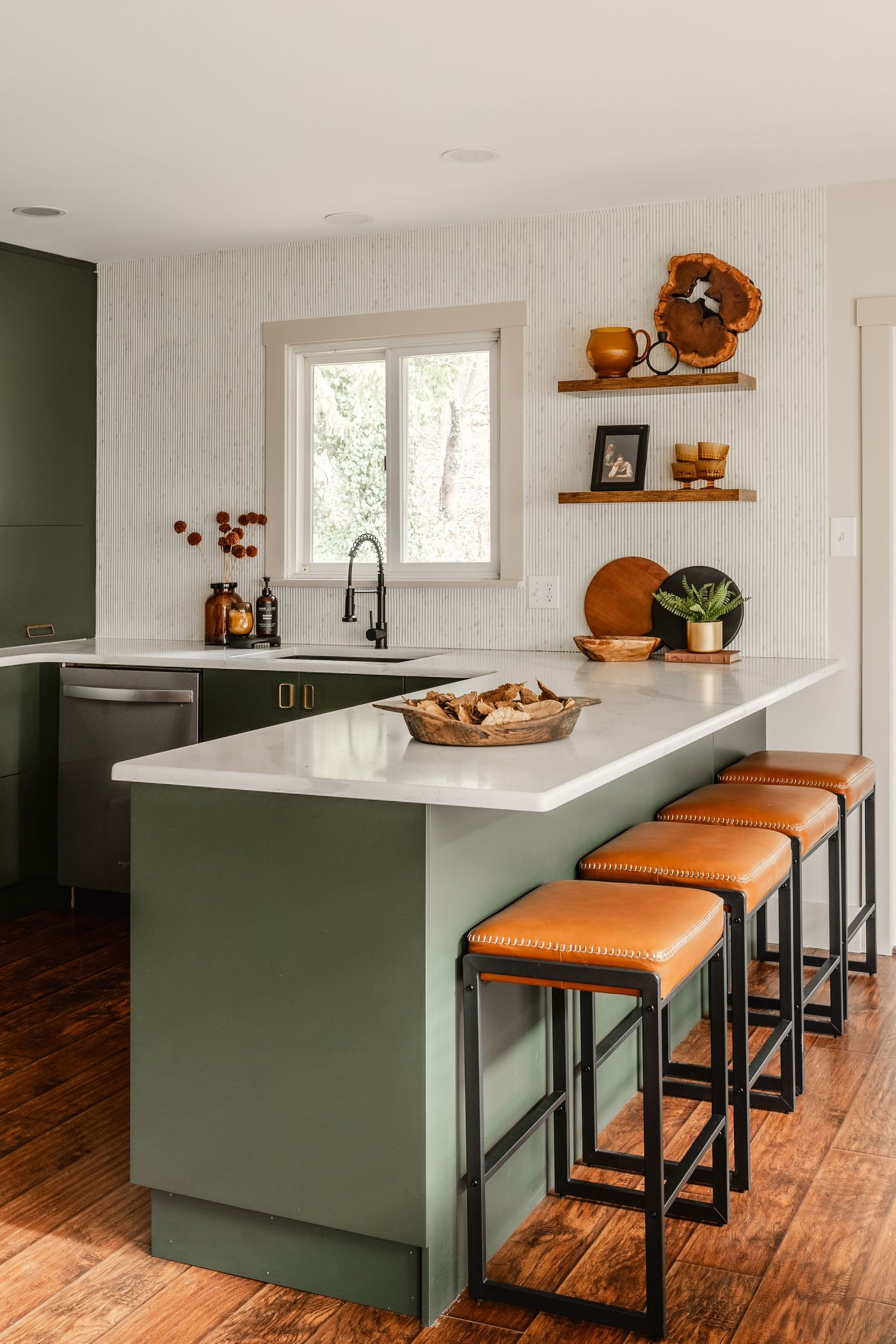 Kitchen island with cognac leather stools facing a round dining table set with taper candles