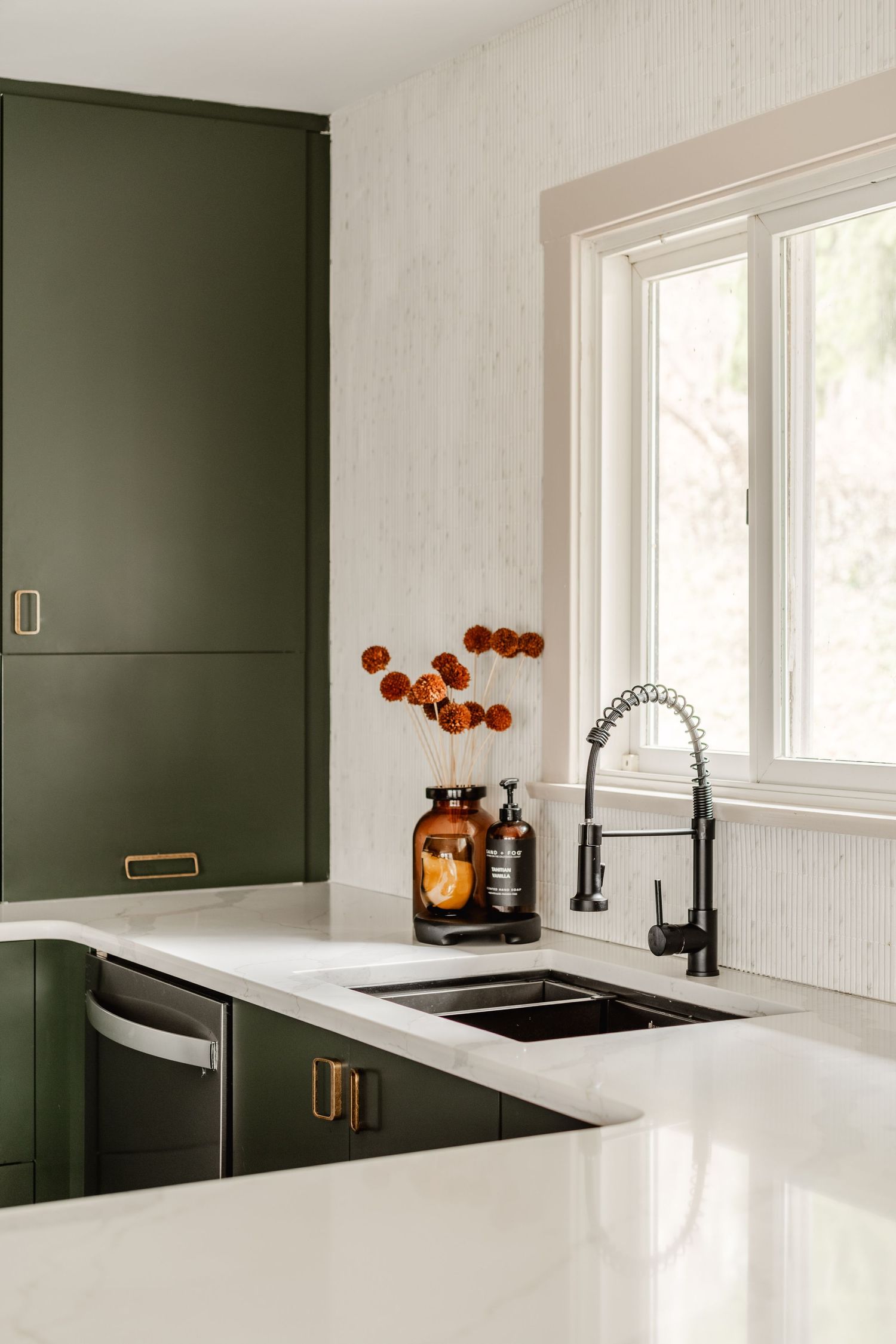 Kitchen sink nook with a black gooseneck faucet, dried flower arrangement and a garden-view window
