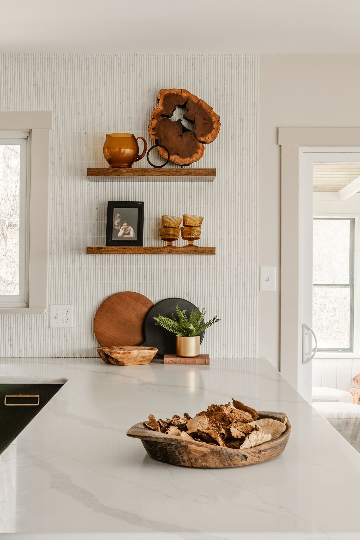 Floating wood shelves styled with an amber glass pitcher, framed portrait and a live-edge wood slab