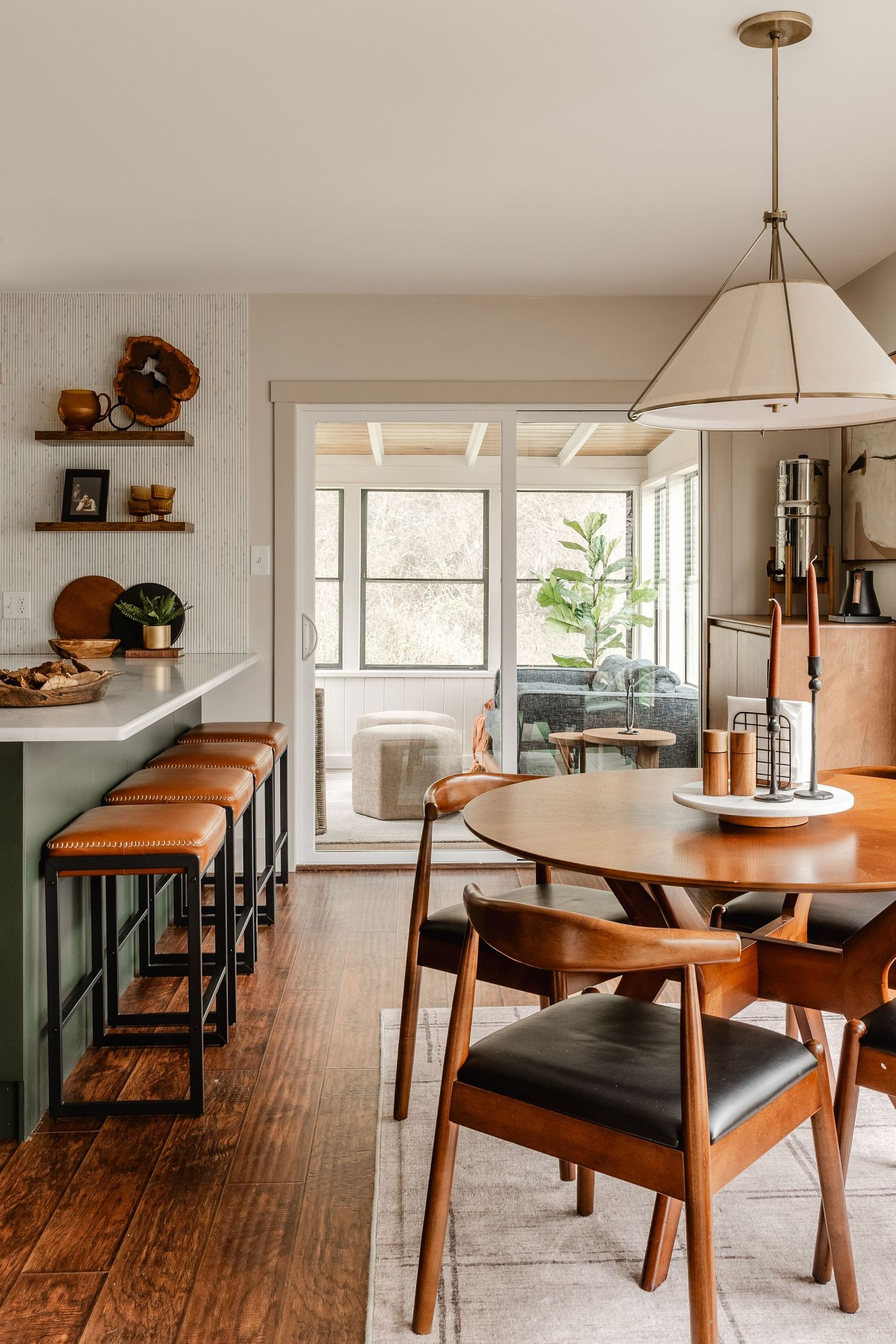 Kitchen bar with cognac stools opens to a dining nook and screened sunporch beyond