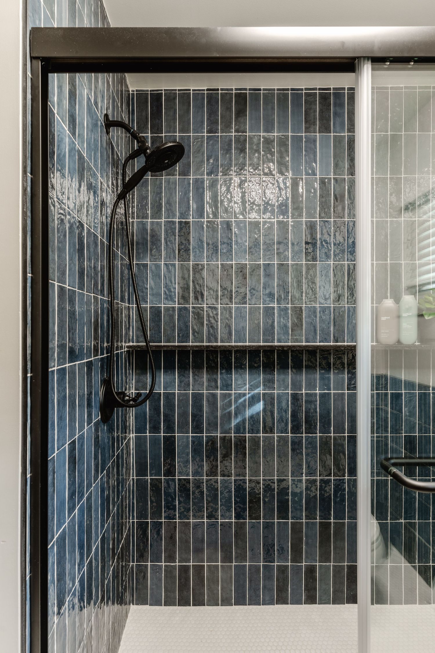 Tiled shower niche shelf styled with body wash bottles and a small potted plant
