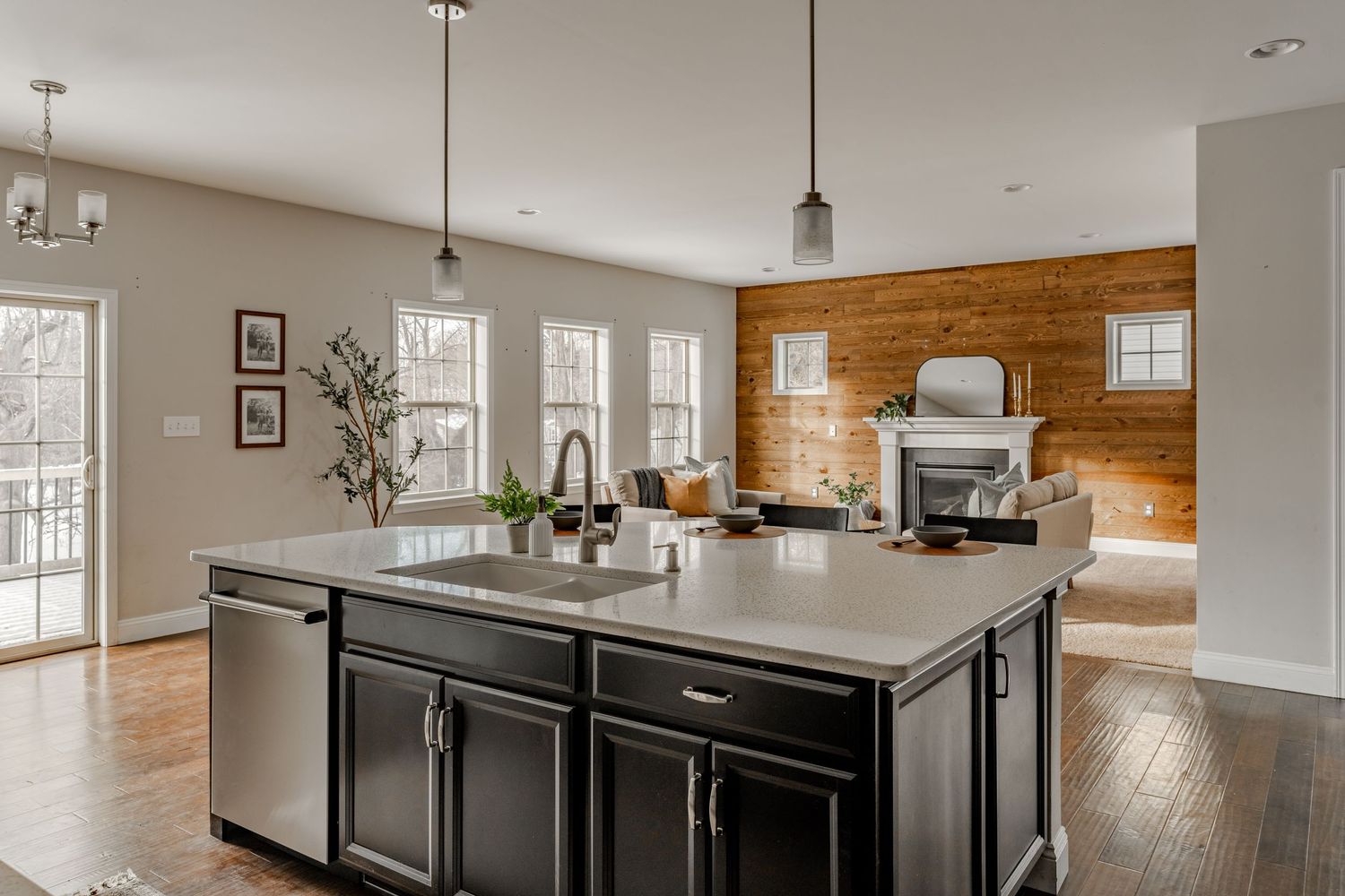 Kitchen island opens to a living room with a shiplap accent wall and white mantel fireplace