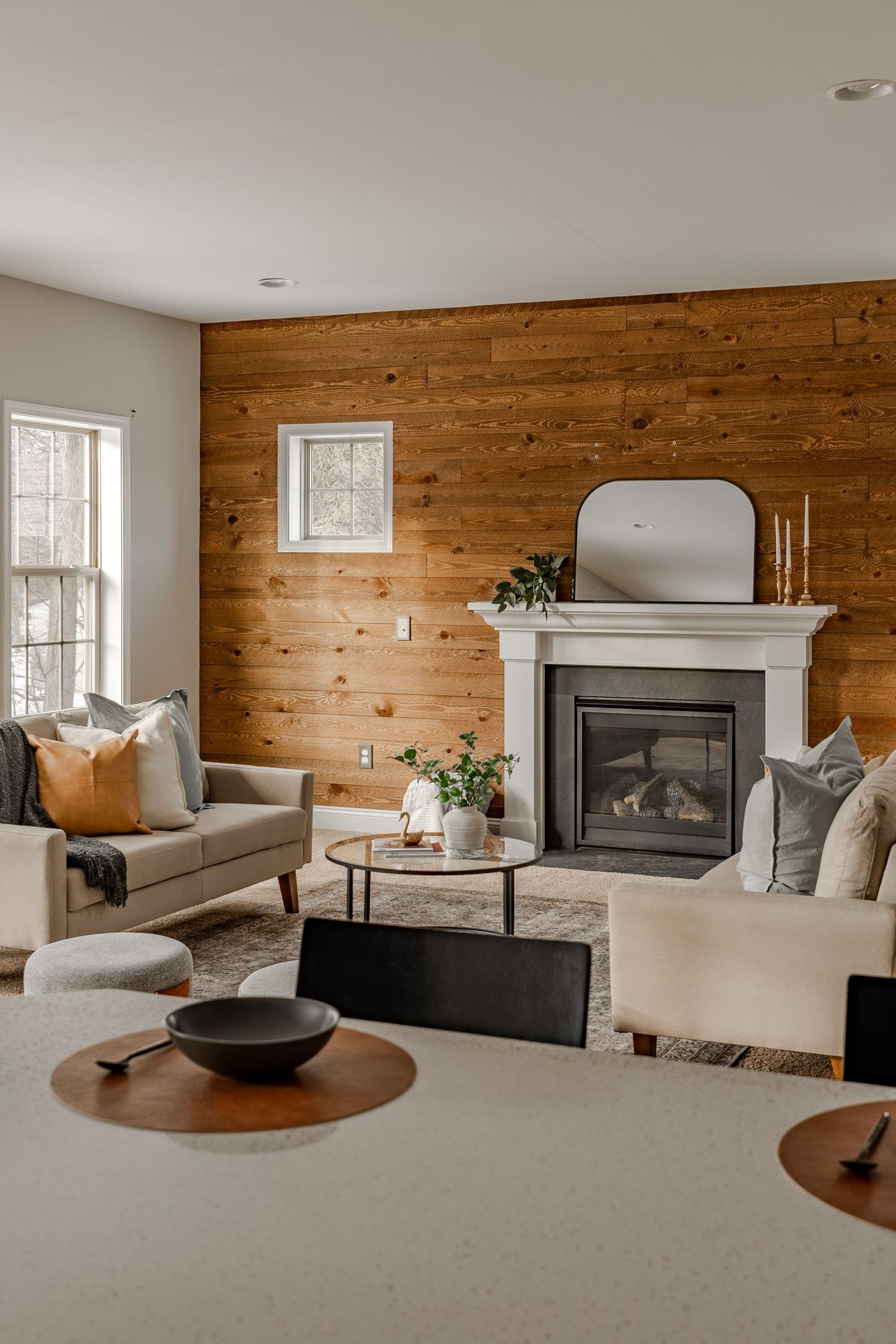 Living room with a wood shiplap accent wall, white fireplace mantel and beige sofas
