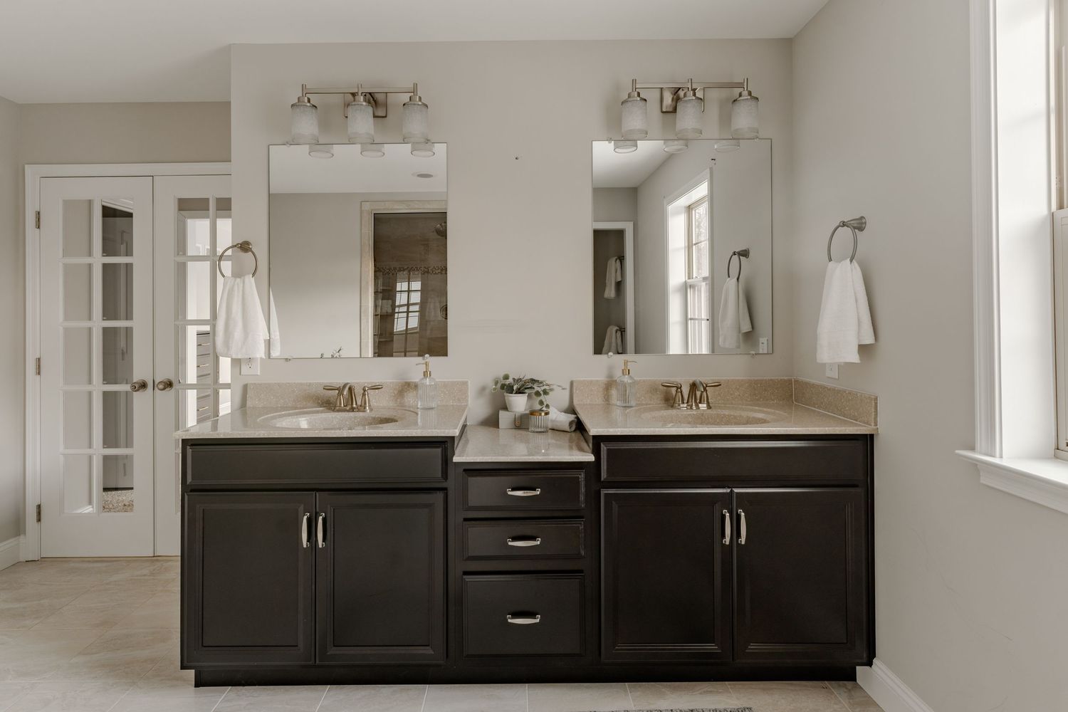 Primary bathroom with a dark wood double vanity, framed mirrors and a French door shower entry