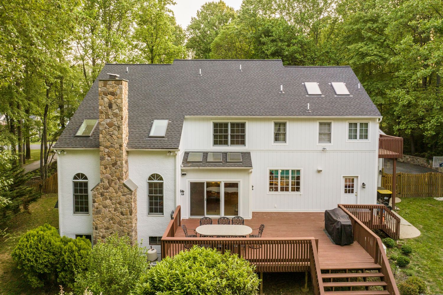Aerial view of a white home's rear addition with skylights above a wraparound wood deck