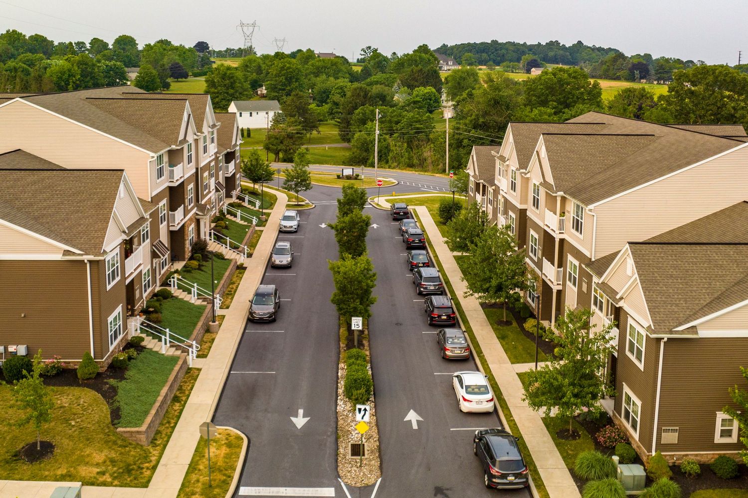 Aerial view of an apartment complex parking lot with rows of parked cars between buildings