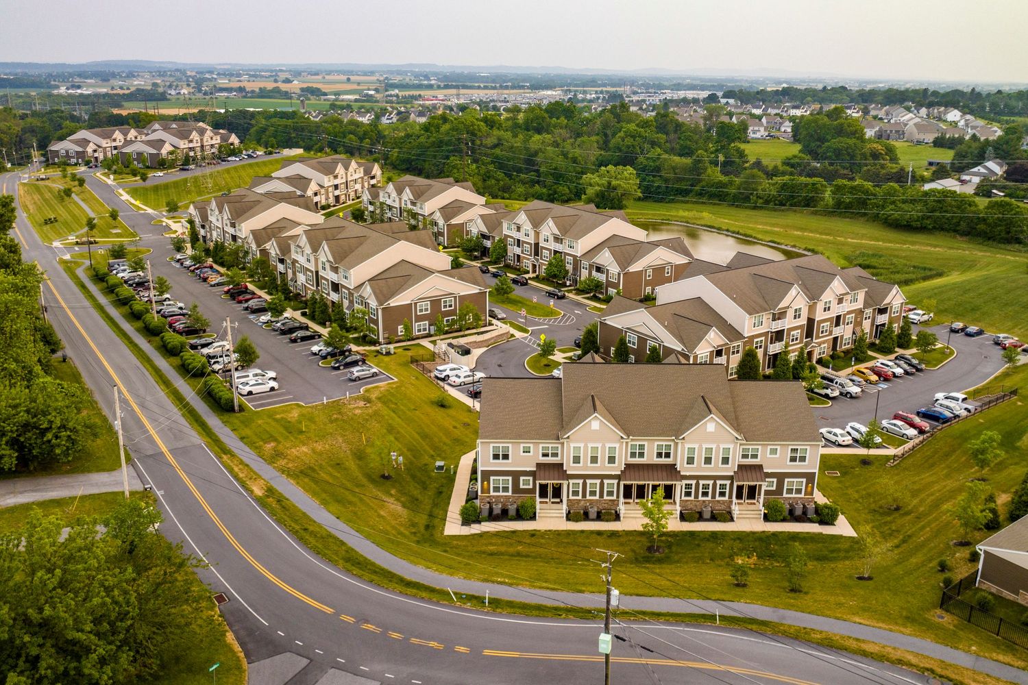 Aerial view of a multi-building apartment complex with parking lots and a retention pond