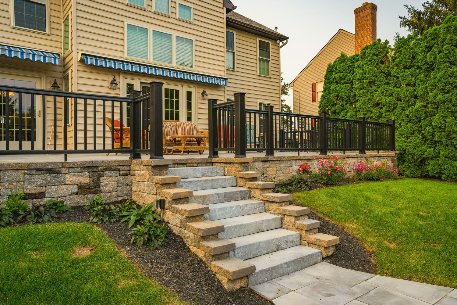 Stone patio steps with a retaining wall, landscape lighting and rose garden beds