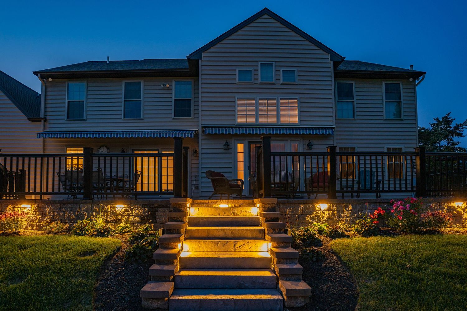 Illuminated stone patio steps leading up to a deck at dusk