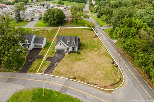 Aerial view of a large grassy home site with property boundary lines traced along the road