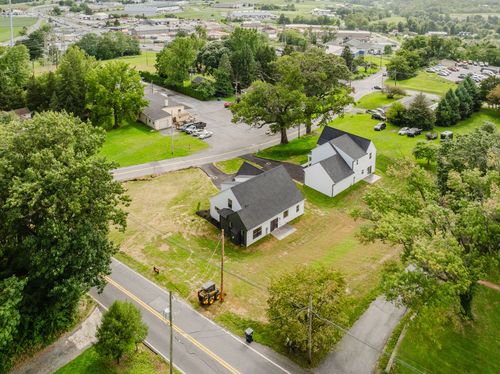 Aerial view of two homes on a grassy corner lot near a road intersection