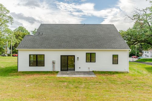 Rear exterior of a white two-story home with black windows and a concrete patio