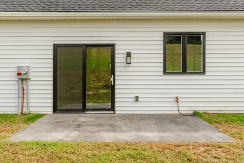 Close view of a black sliding patio door and window on a white sided home