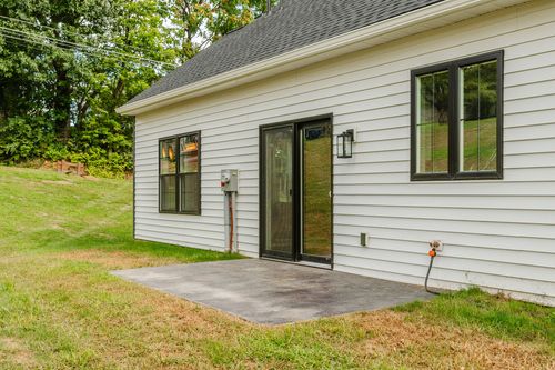 Black sliding glass door leading to a small concrete patio on a new home's exterior