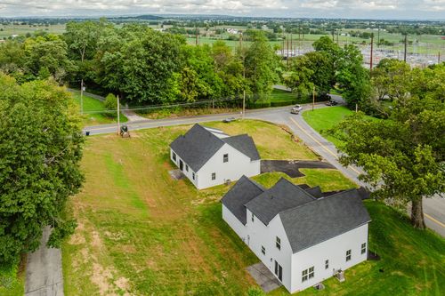 Aerial view of two white homes on a grassy lot near a rural road intersection