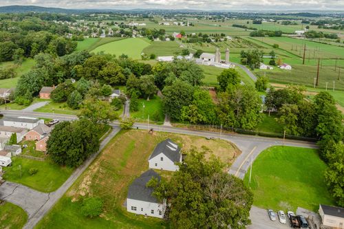 Aerial view of farmland with silos and a distant farmhouse cluster near a country road