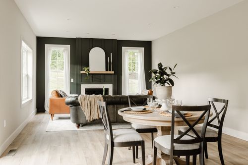 Living and dining space with a black accent wall, fireplace and round dining table