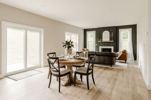 Open dining and living area with a round table, black slider door and leather sofa