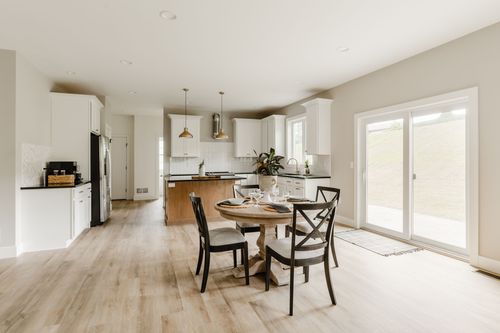 Kitchen and dining space with a round table, white cabinets and a wood island
