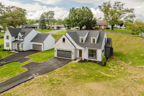 Aerial view of a new home built beside an older farmhouse on a large green lawn in Akron