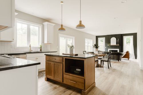Open-concept kitchen with black countertops, a wood island and dining area beyond