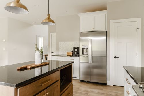 Kitchen with a stainless refrigerator and wood island beneath gold pendant lights