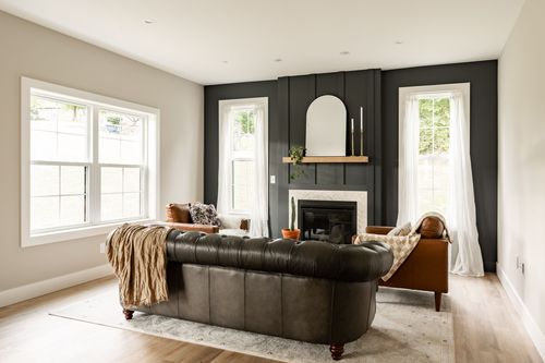 Living room with a dark fireplace wall, arched mirror and brown leather sofas
