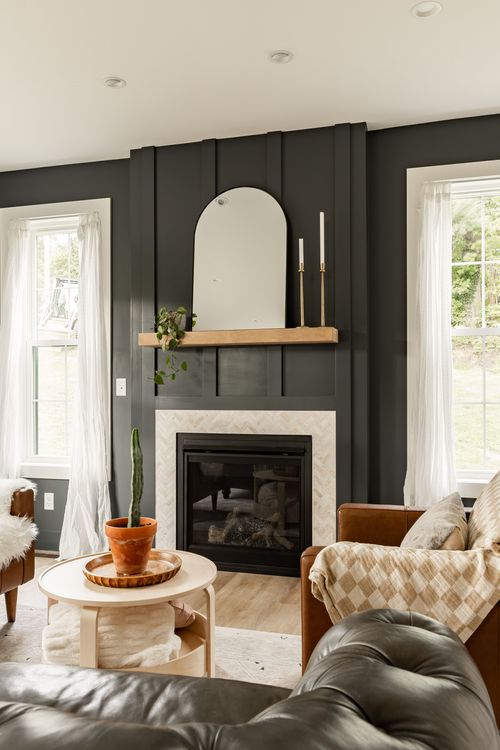 Fireplace with a black paneled wall, wood mantle, arched mirror and tile surround