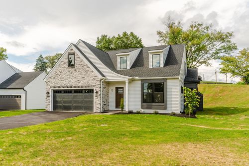 Front exterior of a two-story stone and white sided home with a covered porch and dark trim
