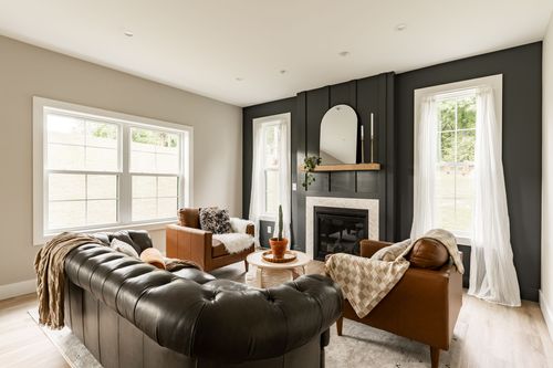 Living room with a black tufted leather sofa and brown leather chairs by the fireplace