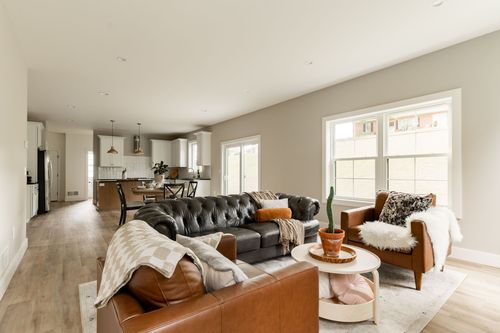 Open living room with leather sofas, a coffee table and the kitchen visible beyond