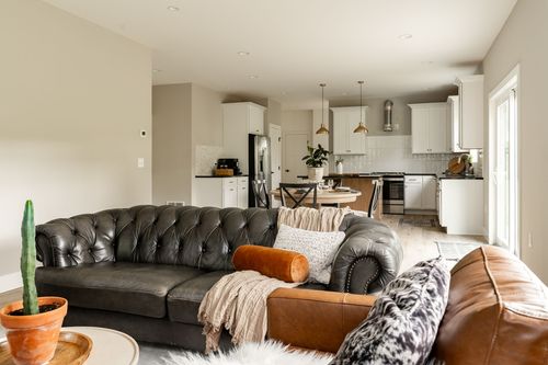 Living room with a tufted leather sofa and open sightline into the kitchen