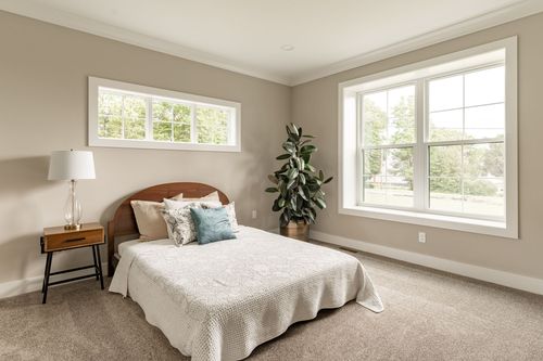 Bedroom with a wood headboard bed, white bedding and two windows