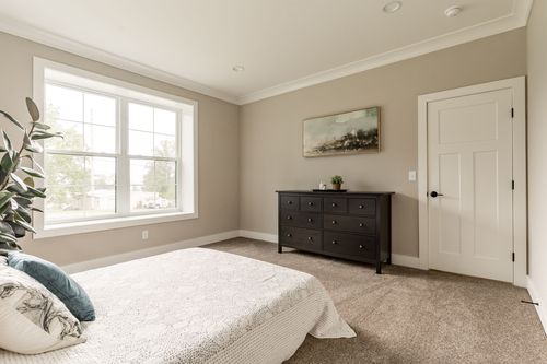 Bedroom with a white bed, dark dresser and framed artwork